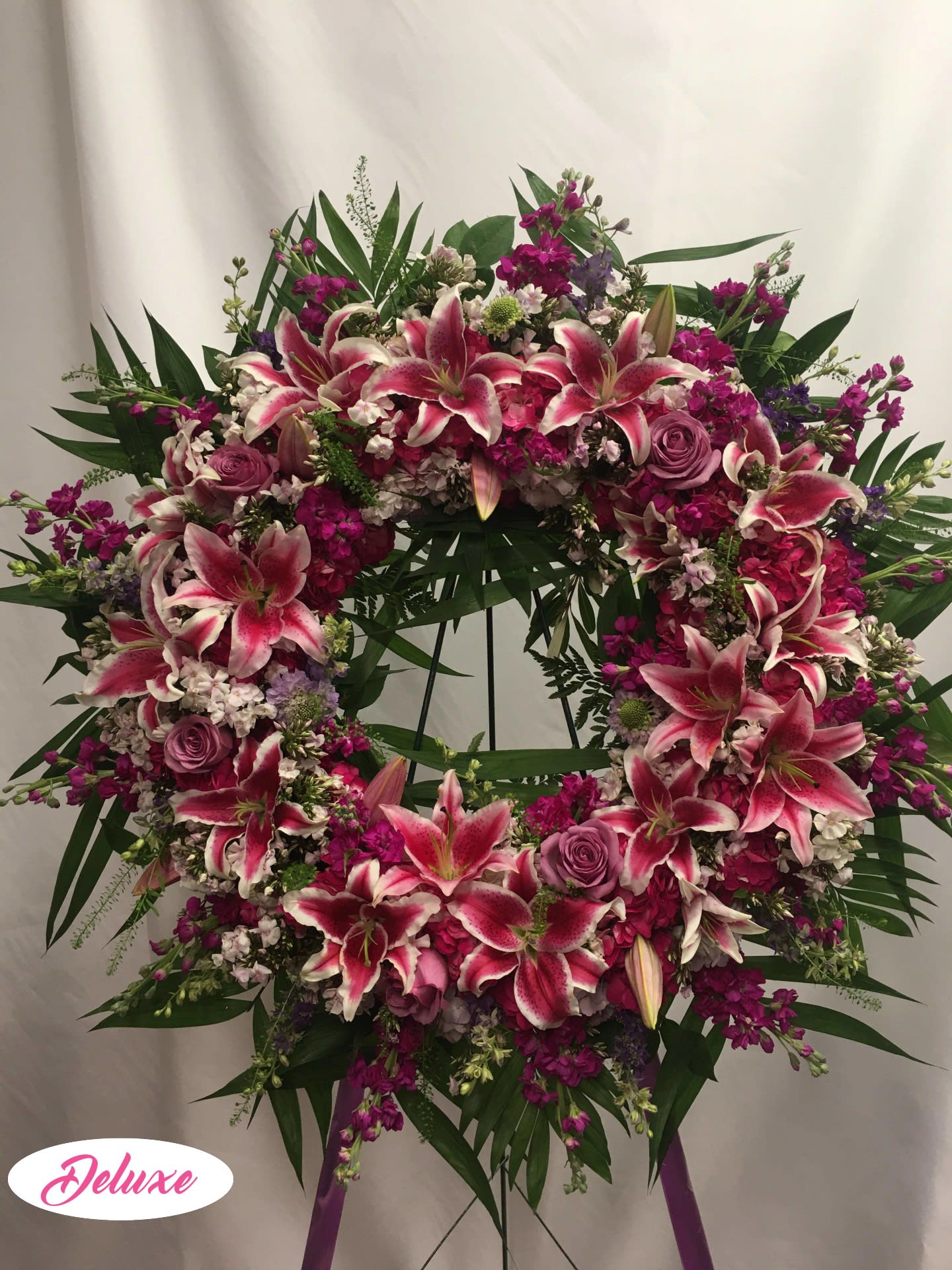 Large pink and white lily wreath with roses on a stand
