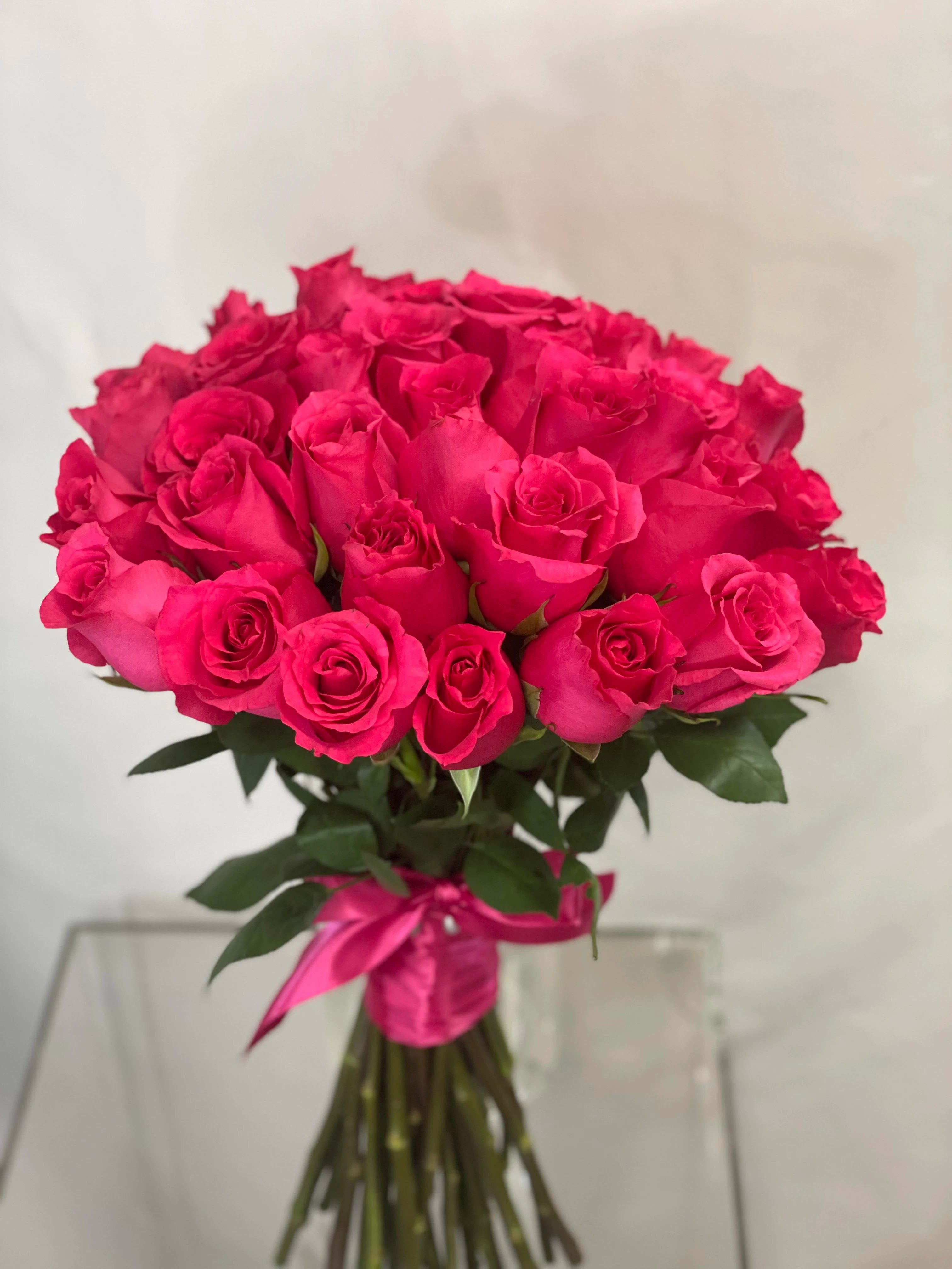 Bouquet of bright pink roses tied with a pink ribbon