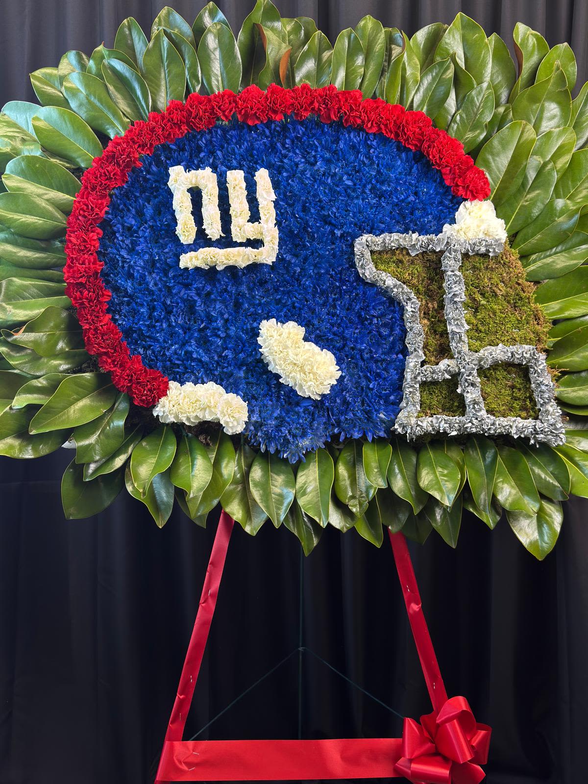 Football-shaped floral tribute with a red border and blue center