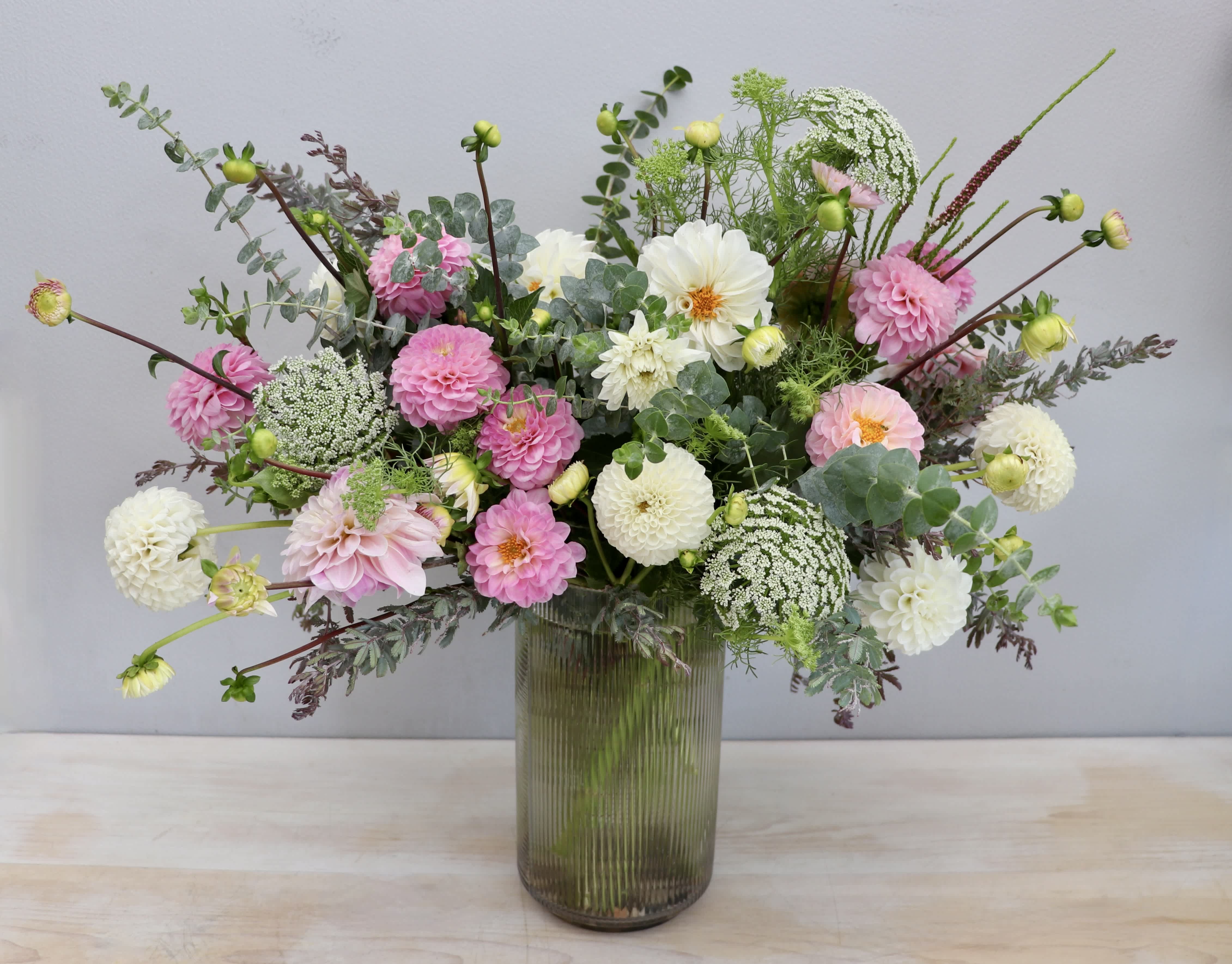 Tall glass vase arrangement of pink and white dahlias with airy filler flowers