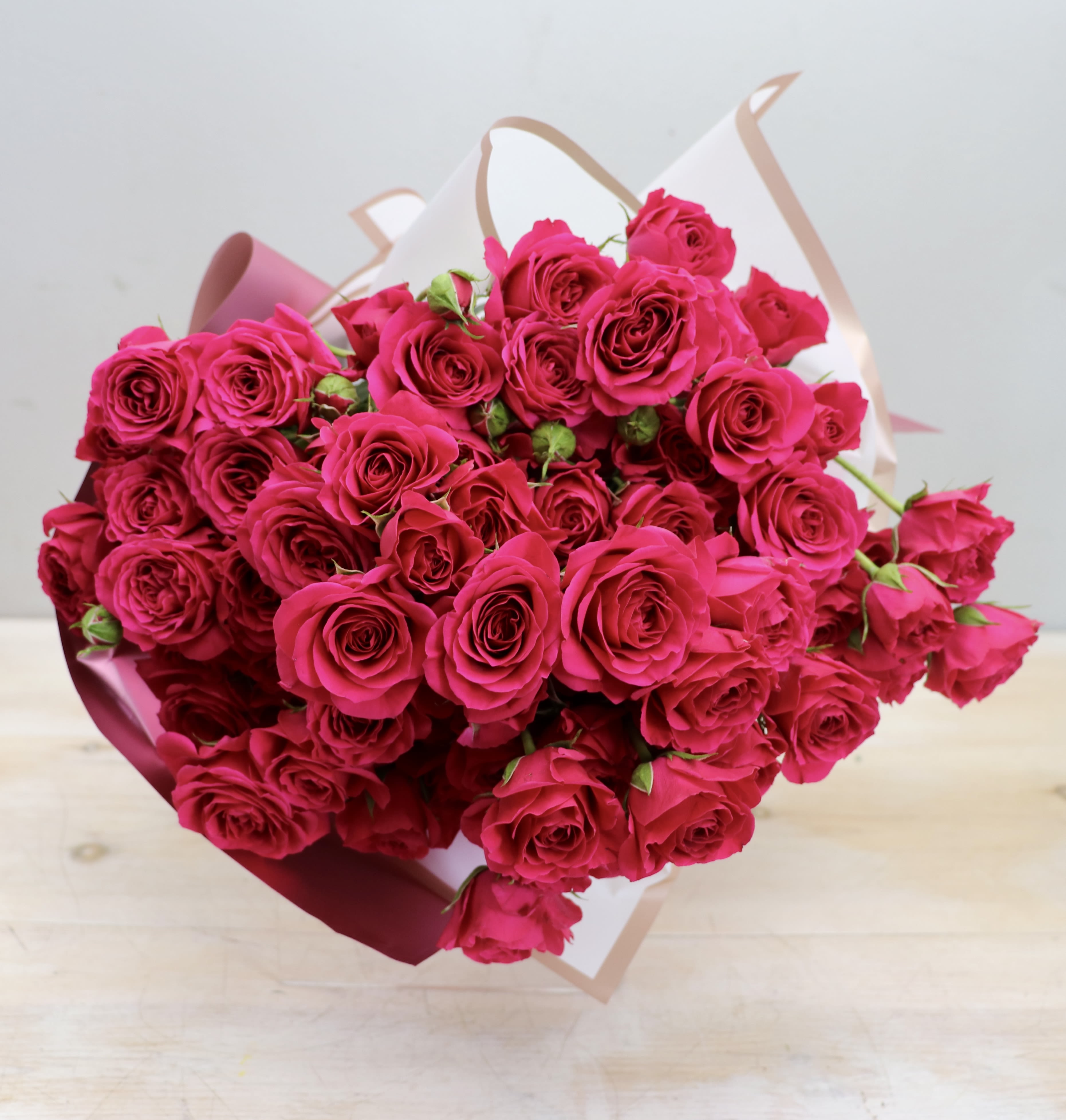 Large bouquet of bright pink roses wrapped in white and pink paper