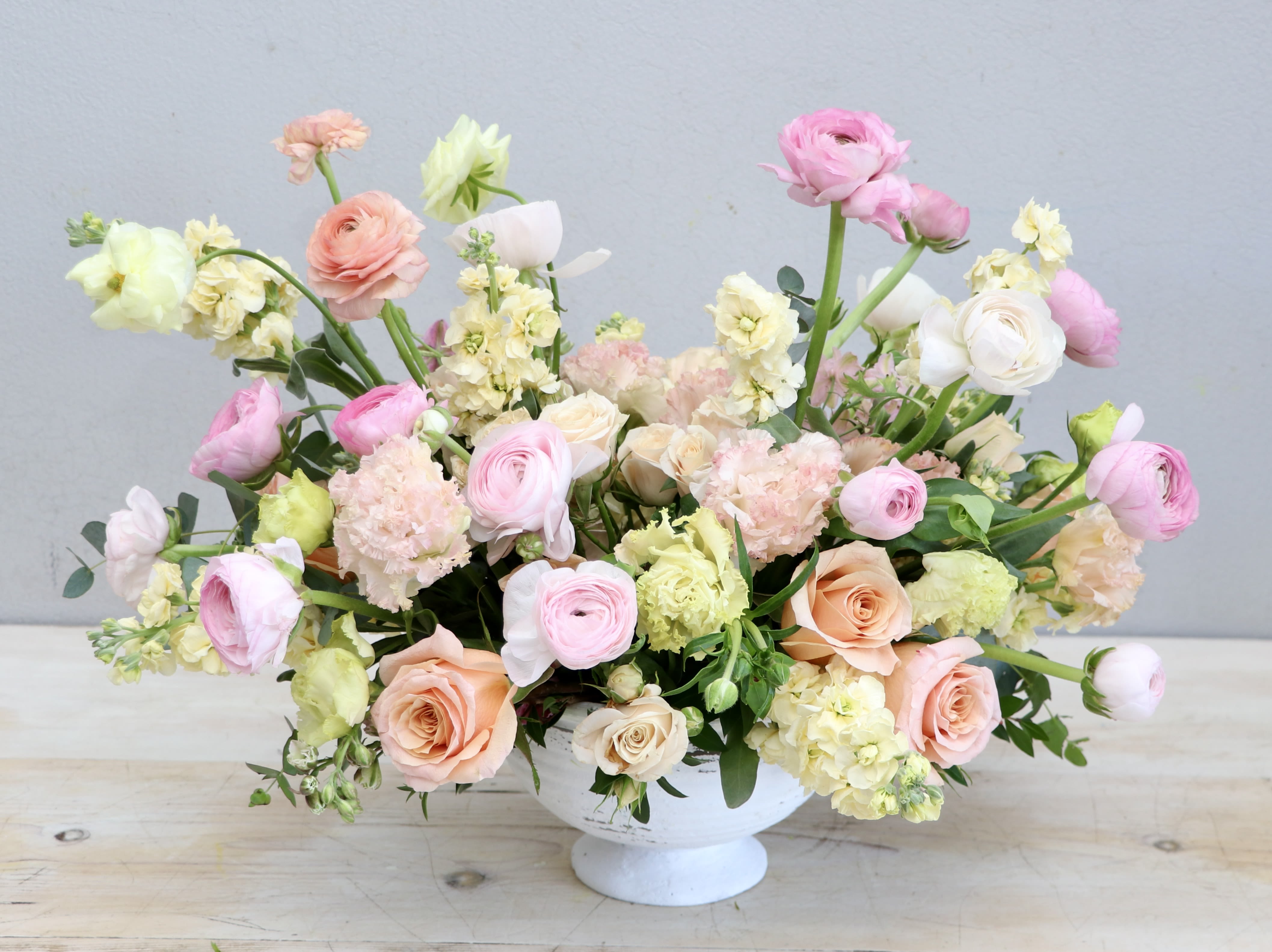 Pastel Waves - Glendale Flowers - Packed with vibrant florals in pastel yellow, pinks and peach hues, this sweet arrangement came just in time for the season. Mixed with ranunculus and seasonal greenery, it stands at approximately 16 inches tall and wide.  
