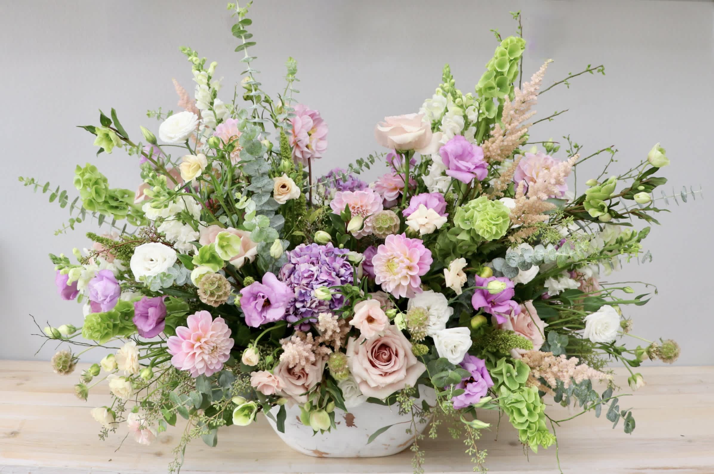 Enchanted Horizon - Glendale Flowers - Designed to make a stunning statement, this sprawling, garden-style arrangement features an airy palette of soft blush pinks, dusty roses, romantic lavenders, and deep lilac hues set against fresh, textural greenery.