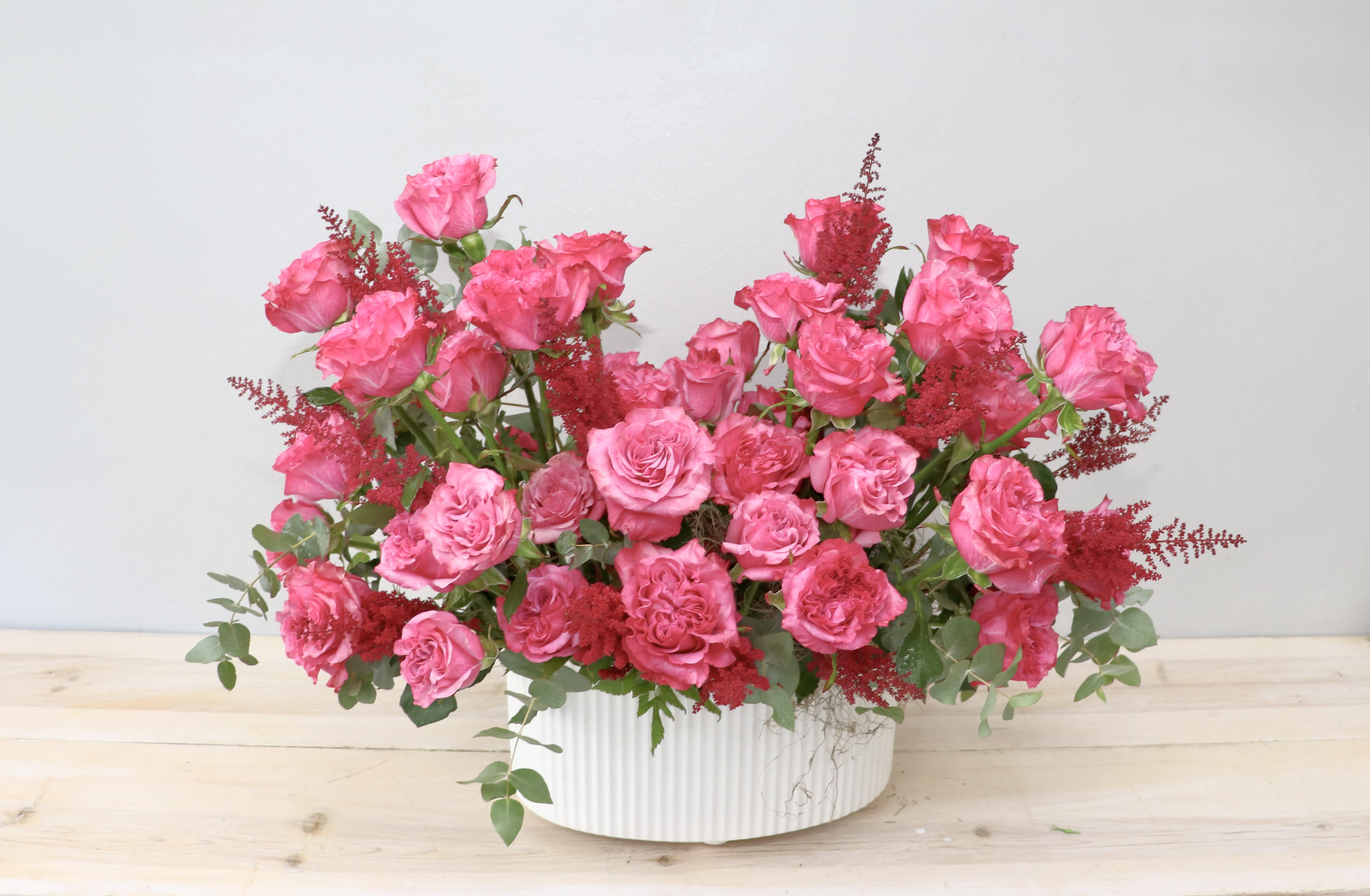 Pink rose arrangement in a white ribbed vase