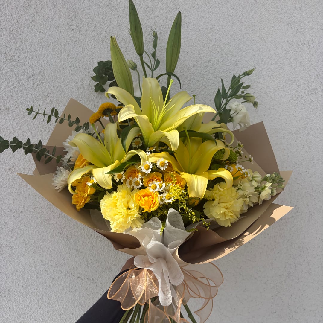 Yellow lily bouquet with mixed white and yellow flowers wrapped in brown paper