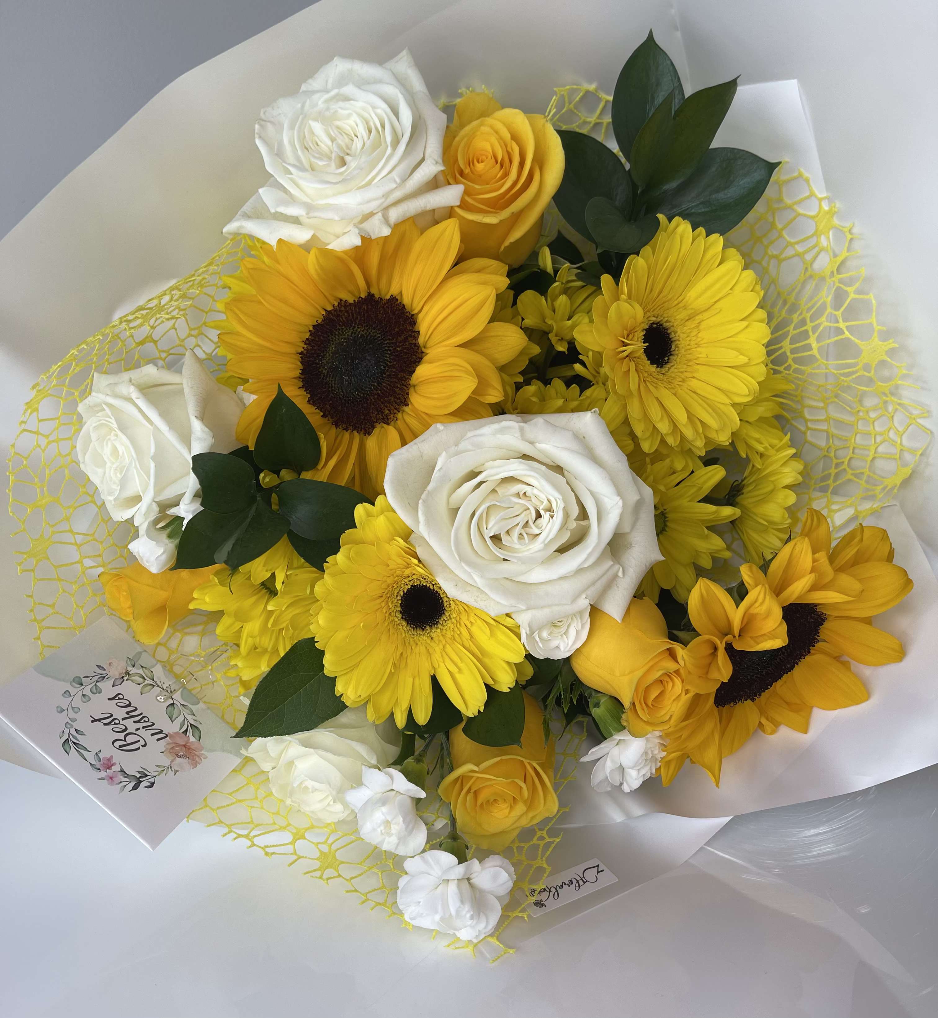 Bouquet of yellow sunflowers and white roses wrapped in white paper