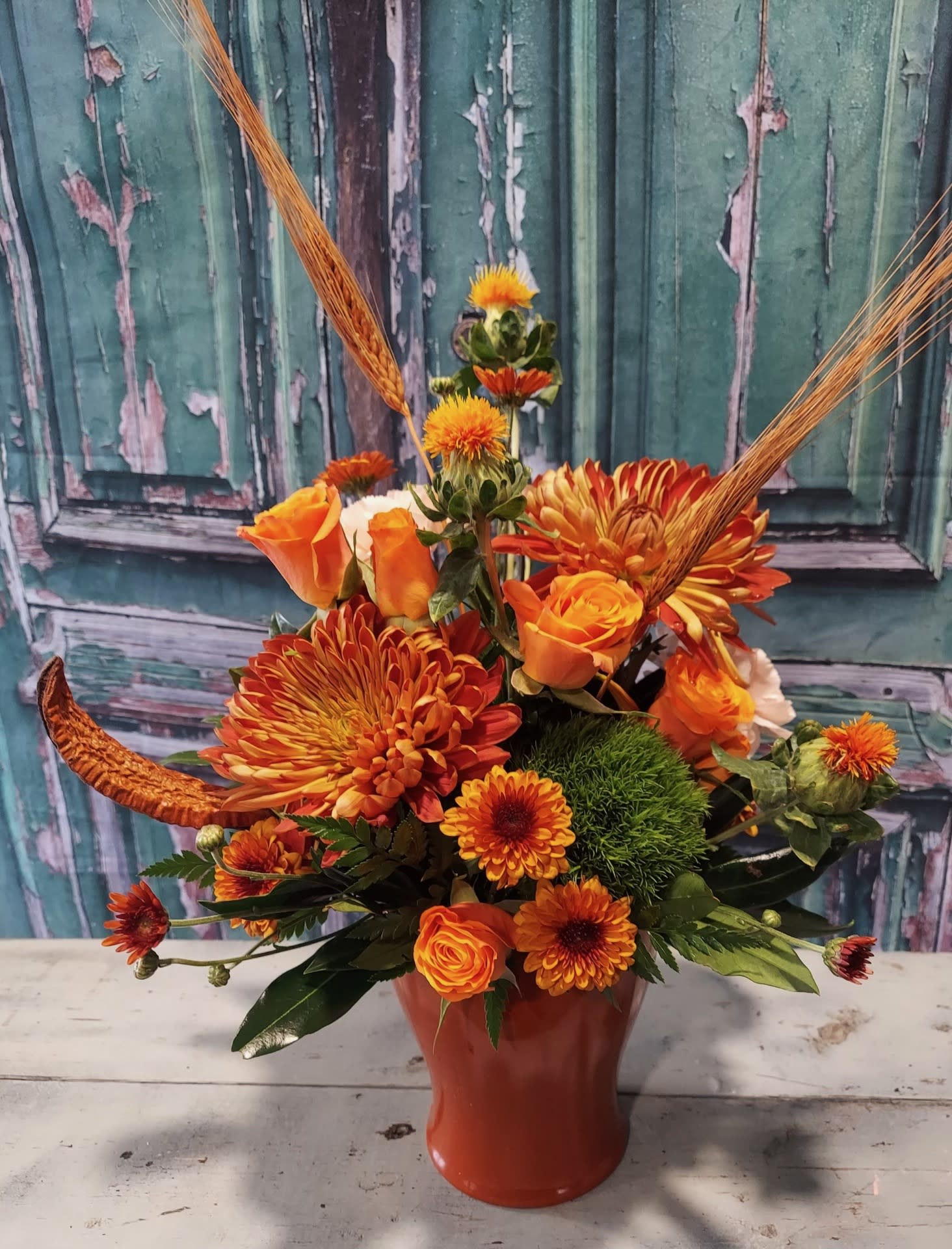 Orange floral arrangement in a red vase with chrysanthemums and roses