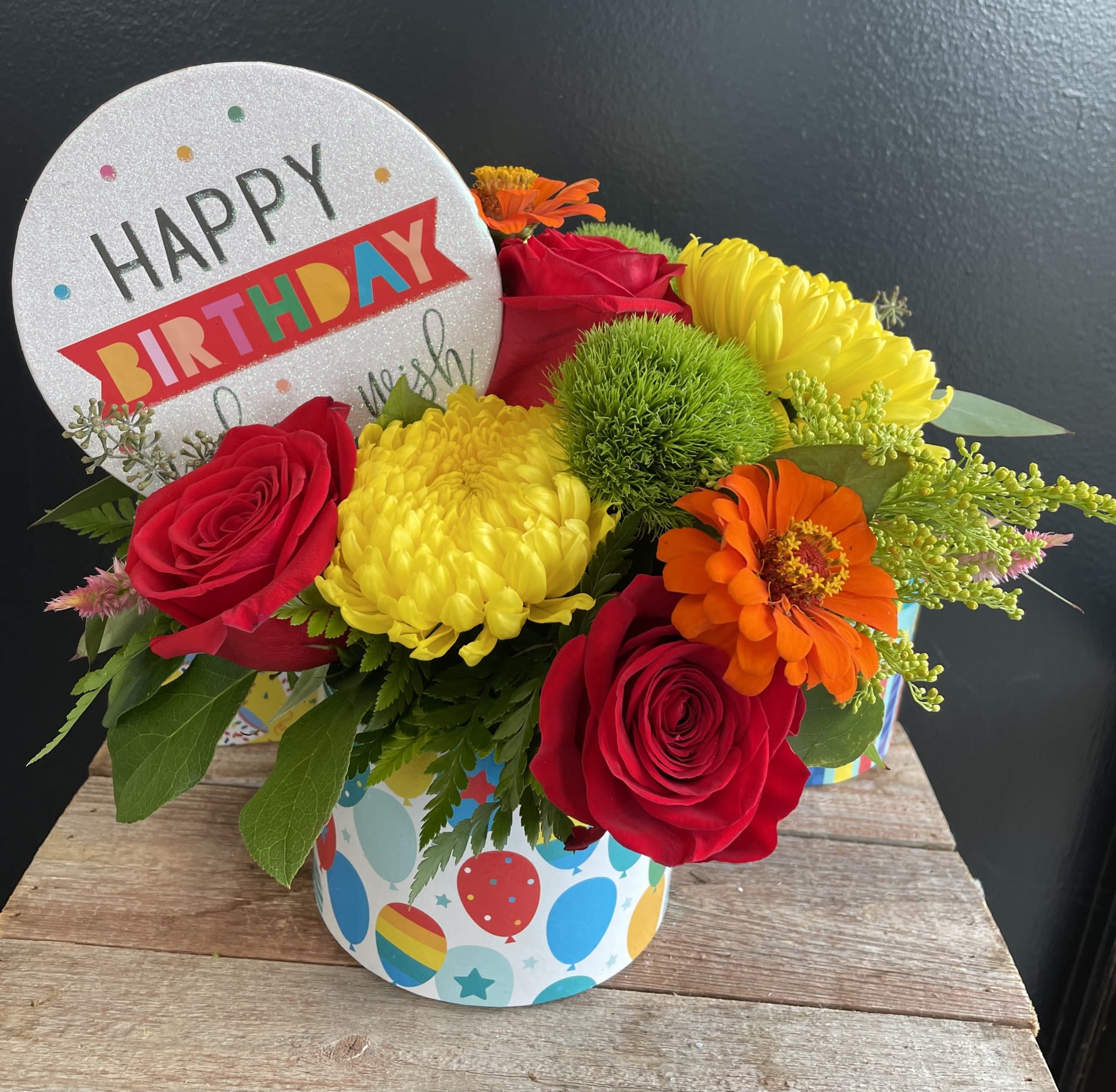 Birthday flower arrangement with roses, mums, and a greeting card topper