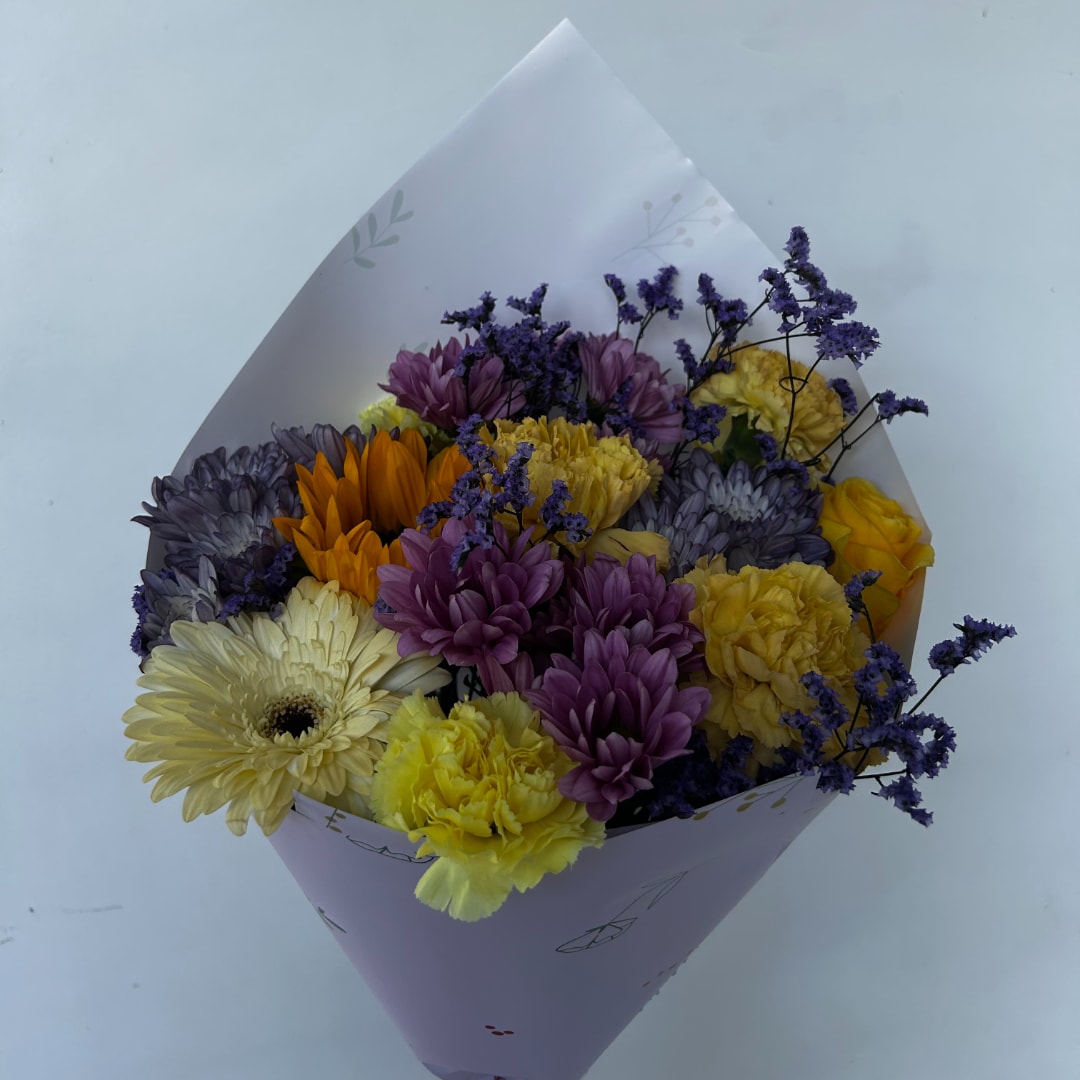 Bouquet of purple, yellow, and white flowers wrapped in pale paper