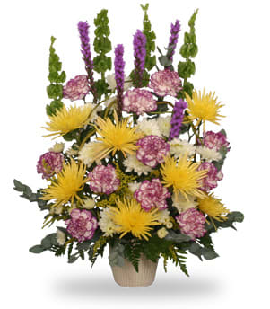 Tall mixed flower arrangement in a beige vase with yellow and purple blooms