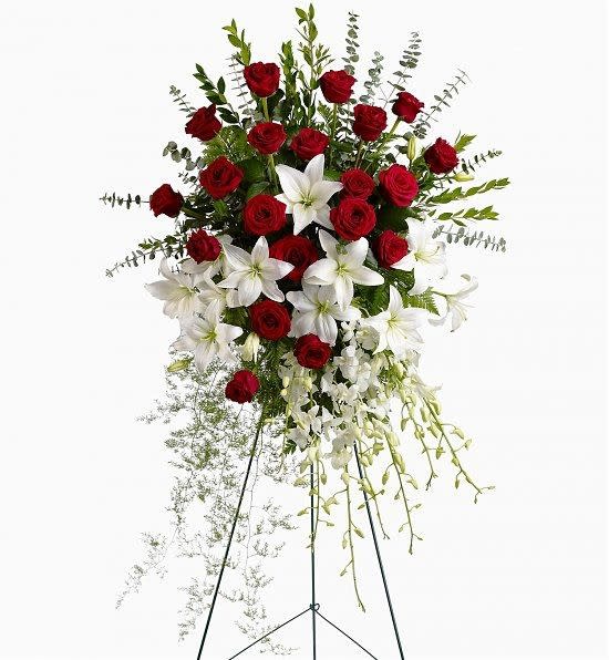 Standing floral spray with red roses and white lilies on a metal easel