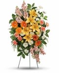 Standing floral spray with yellow lilies, orange daisies, and pink flowers