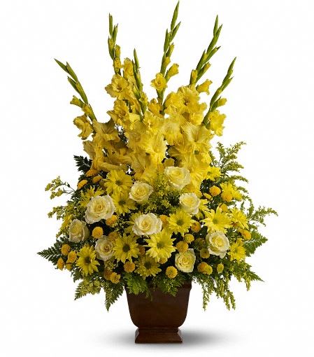 Tall yellow and white floral arrangement with gladiolus, roses, and daisies in a brown urn