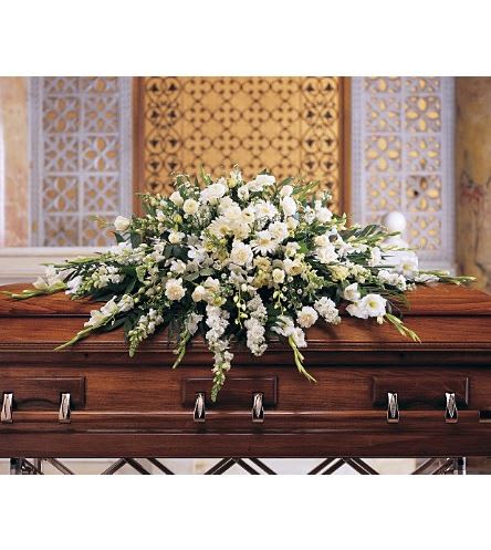 White floral casket spray arranged on a polished wood coffin