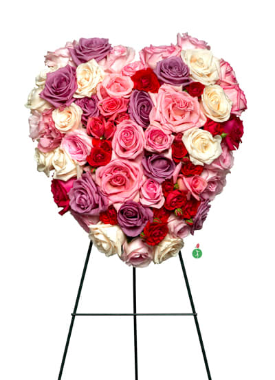 Heart-shaped arrangement of pink, red, lavender, and cream roses on a metal easel stand