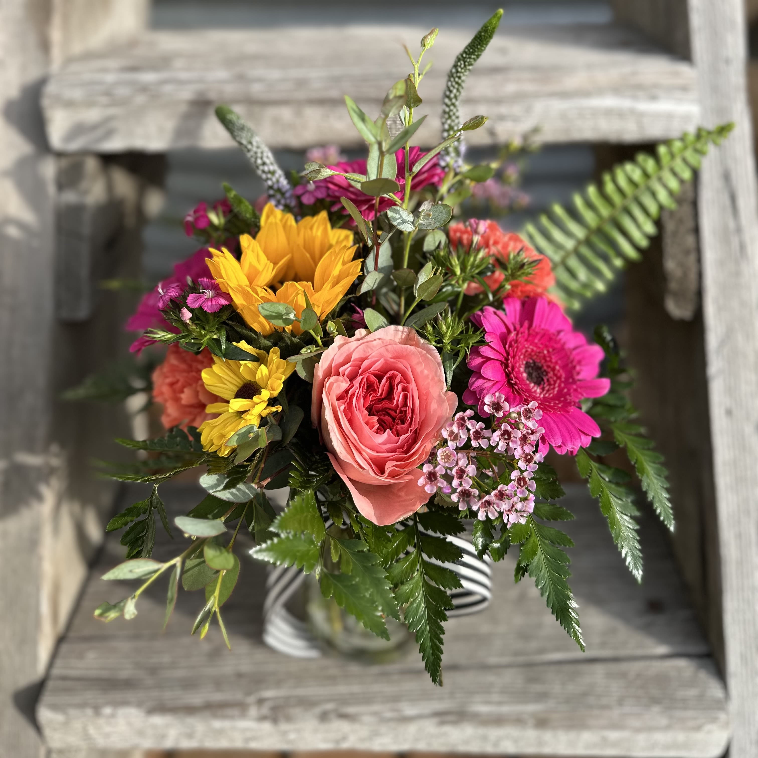 Mixed bouquet with pink and yellow flowers in a striped vase