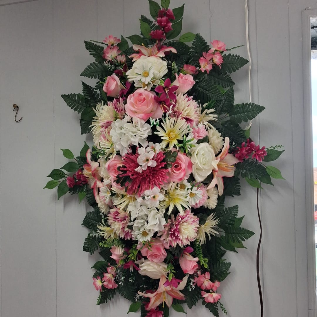 Tall floral spray with pink and white flowers against a wall