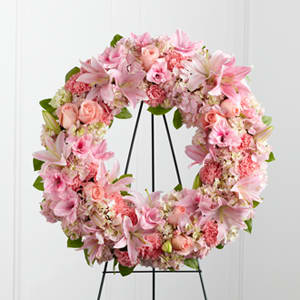 Pink floral wreath with lilies and roses on a black stand