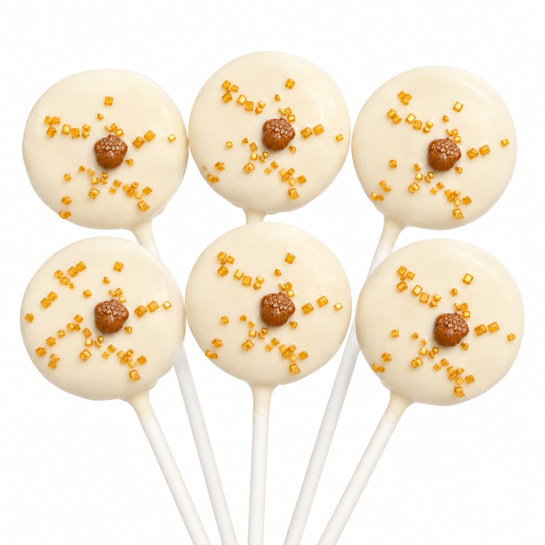 Six white cake pops with amber sprinkles on sticks