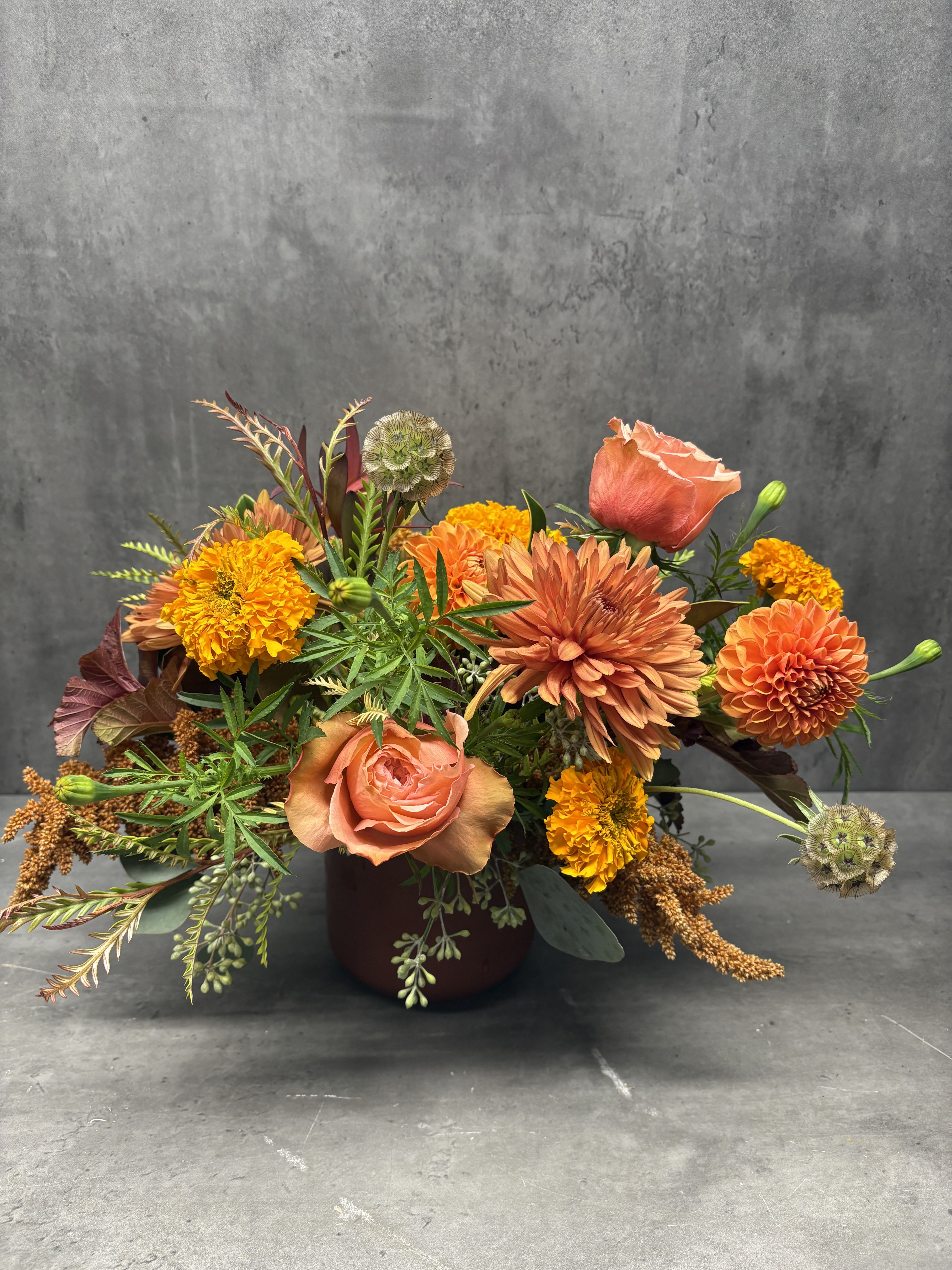 Orange and peach mixed bouquet in a dark vase