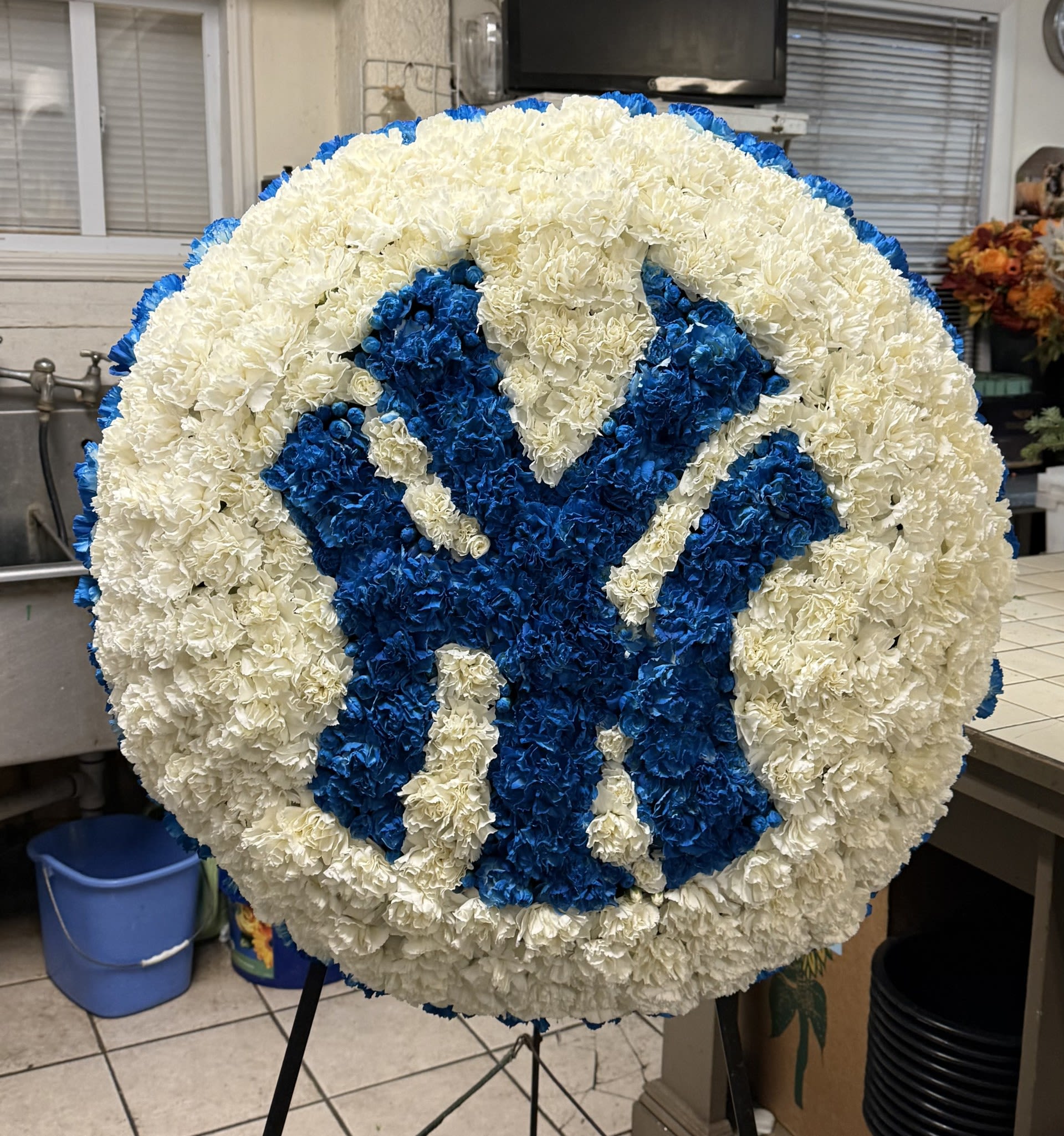 Round floral tribute with a blue and white monogram design