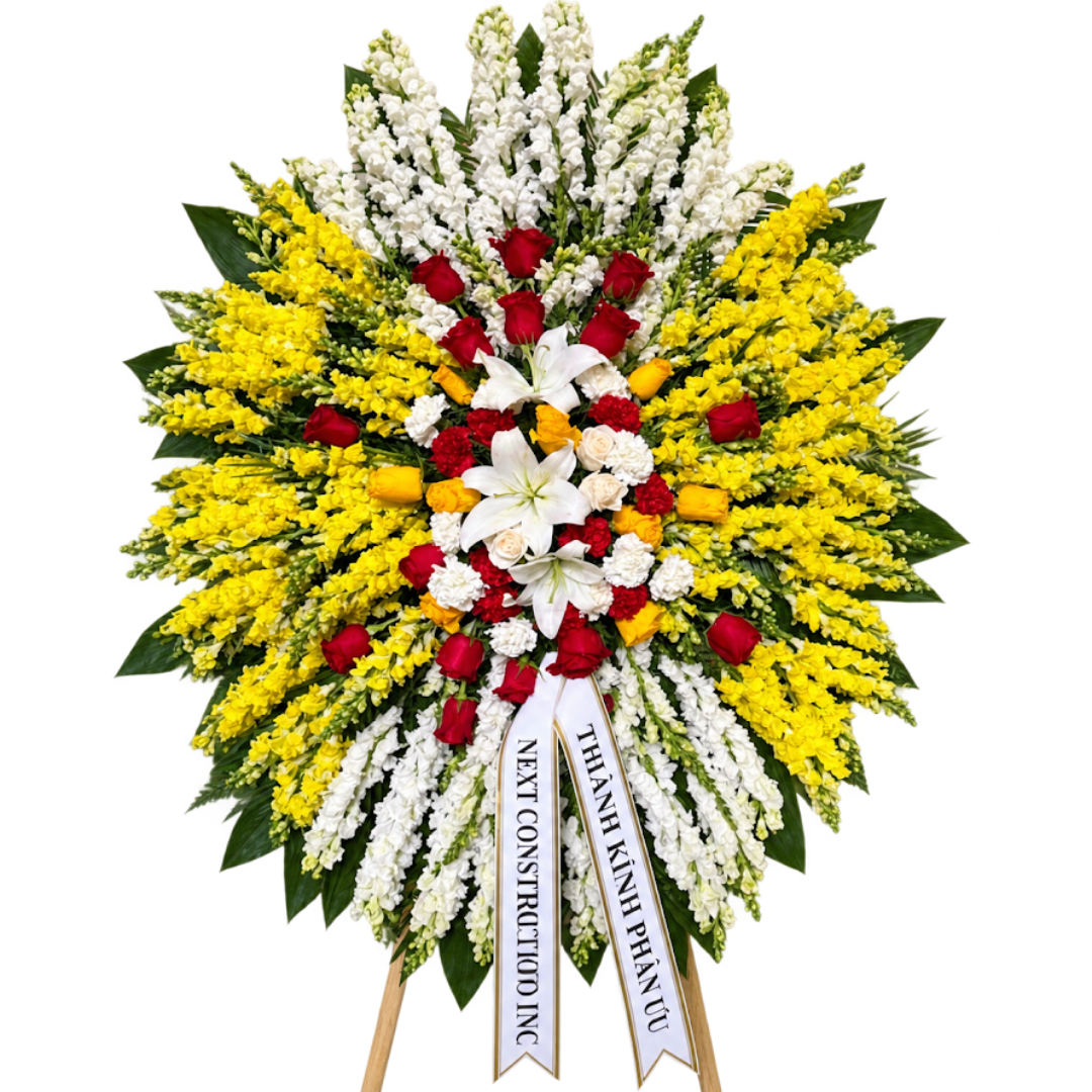 Large standing floral wreath with red, white, and yellow flowers on ribbons