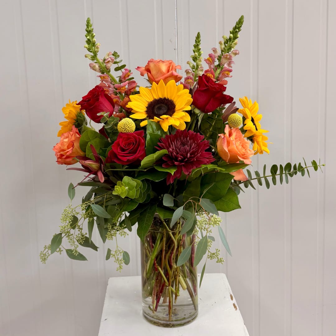 Mixed bouquet in a clear glass vase with sunflowers and red roses