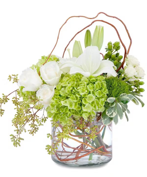 White lilies and green hydrangeas in a glass vase with curly branches