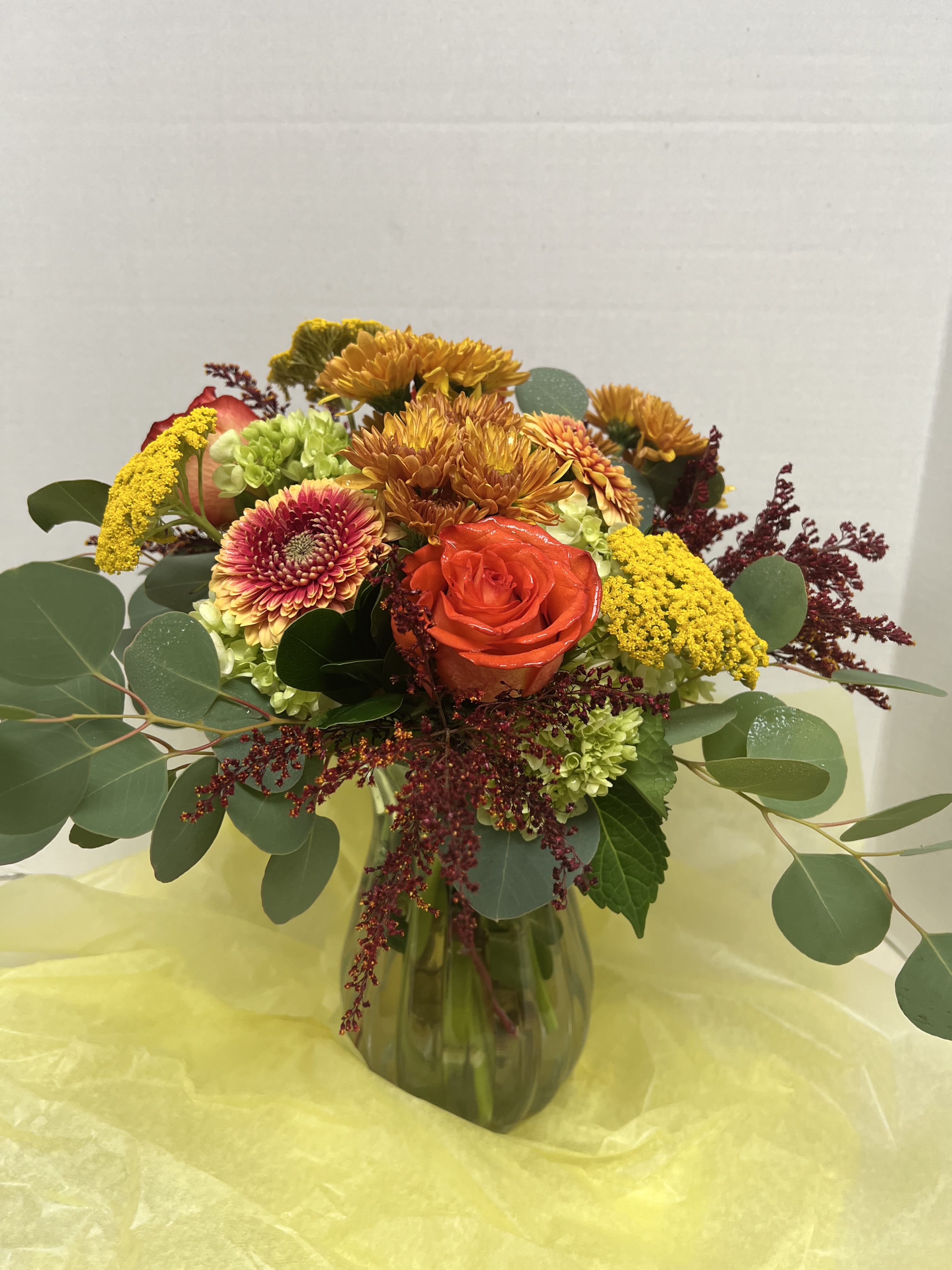 Mixed bouquet in a glass vase with orange roses and yellow chrysanthemums