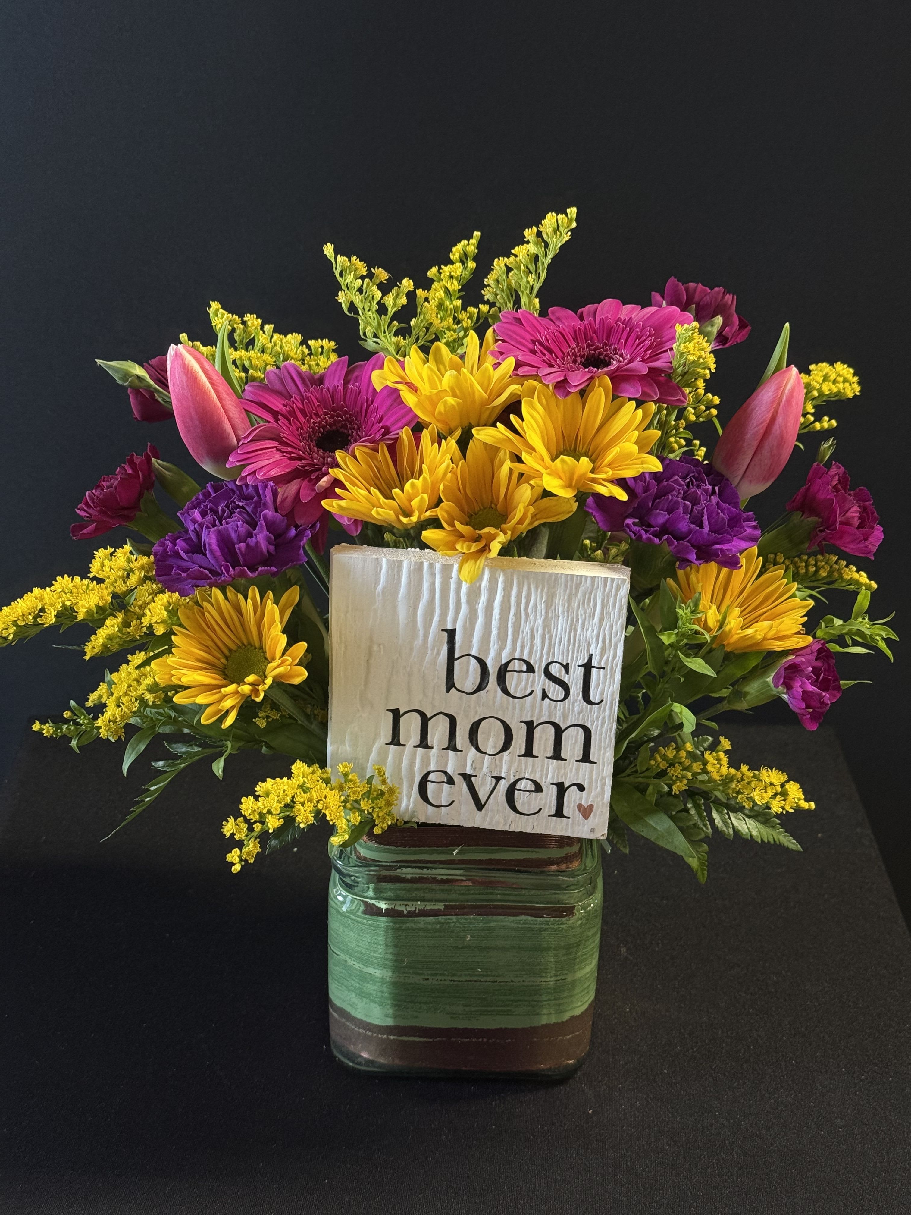 Best Mom Ever! - Bright yellow daisies, pink tulips and purple accents in a clear glass vase with carnations and a "best mom ever" sign-cheerful, giftable Mother's Day bouquet.