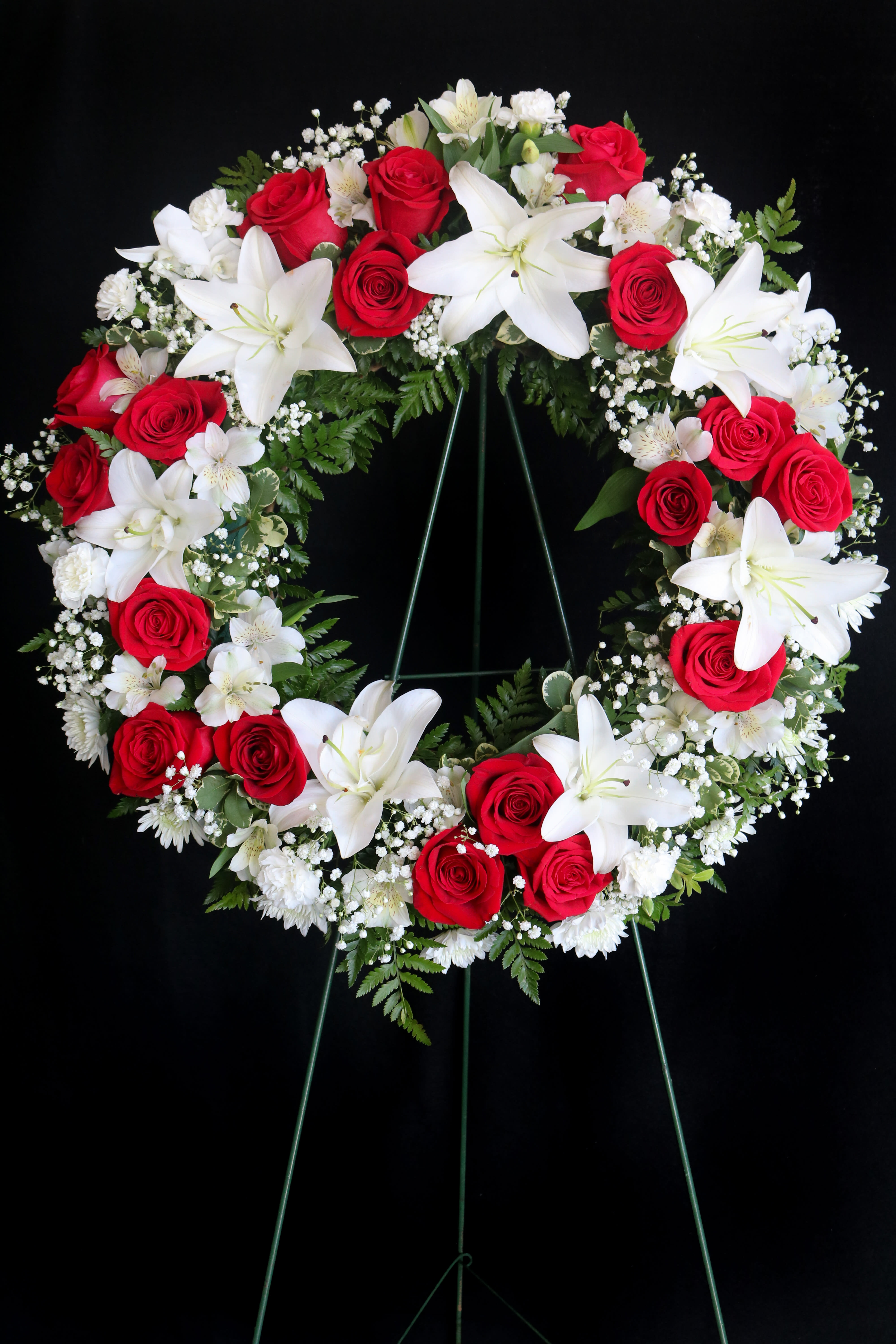 Red roses and white lilies arranged in a circular funeral wreath