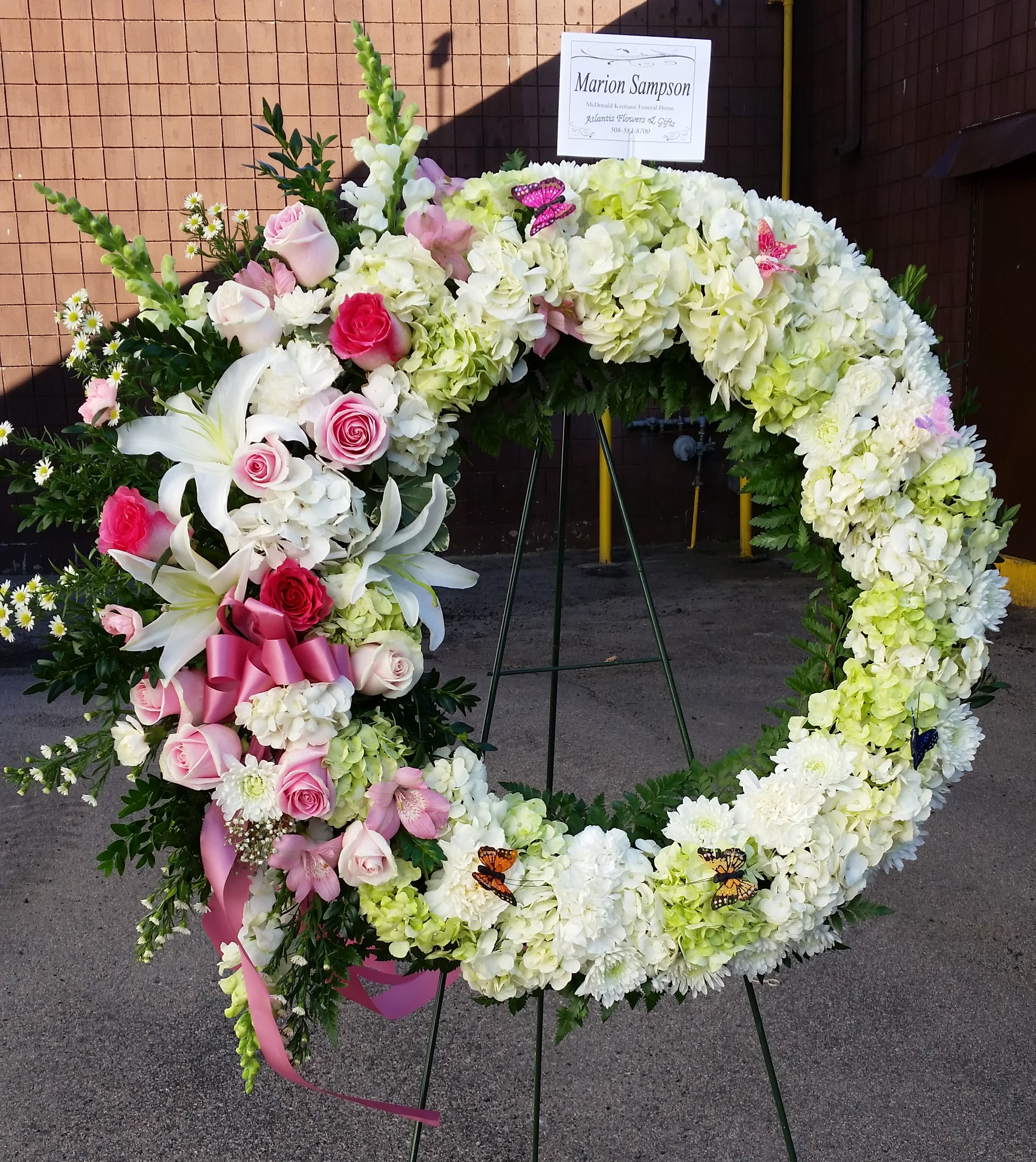 Heart-shaped floral wreath with pink and white flowers on an easel