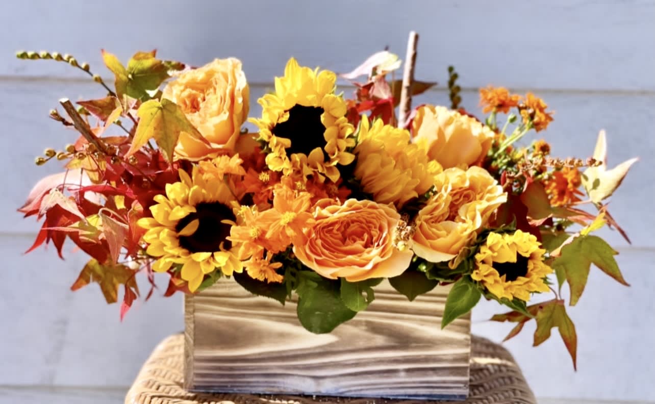 Autumn bouquet of yellow sunflowers and orange roses in a striped vase