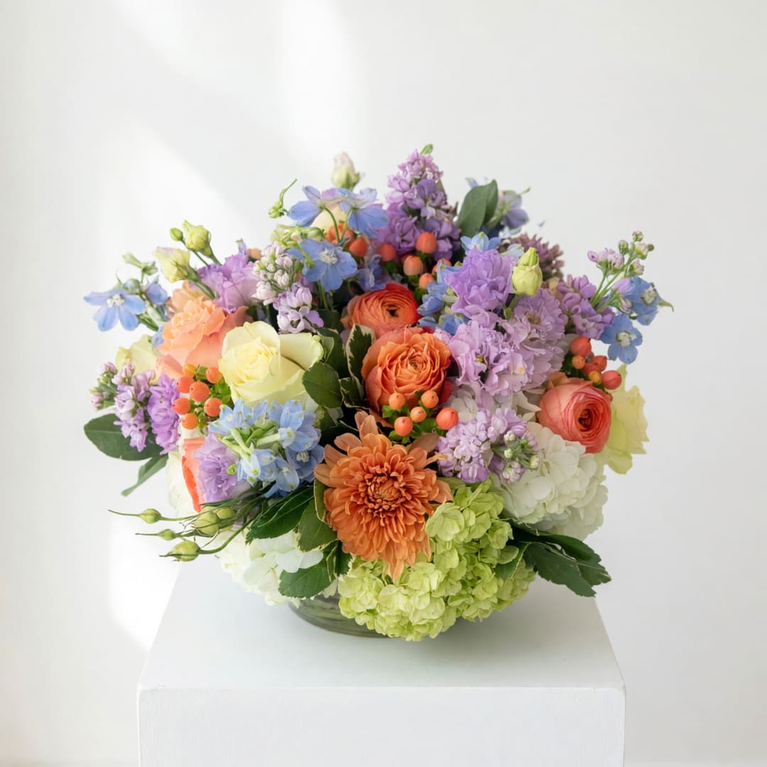 Colorful mixed flower arrangement in a low glass bowl
