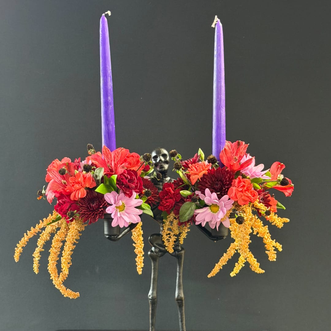 Floral arrangement with two purple taper candles on a skeleton stand