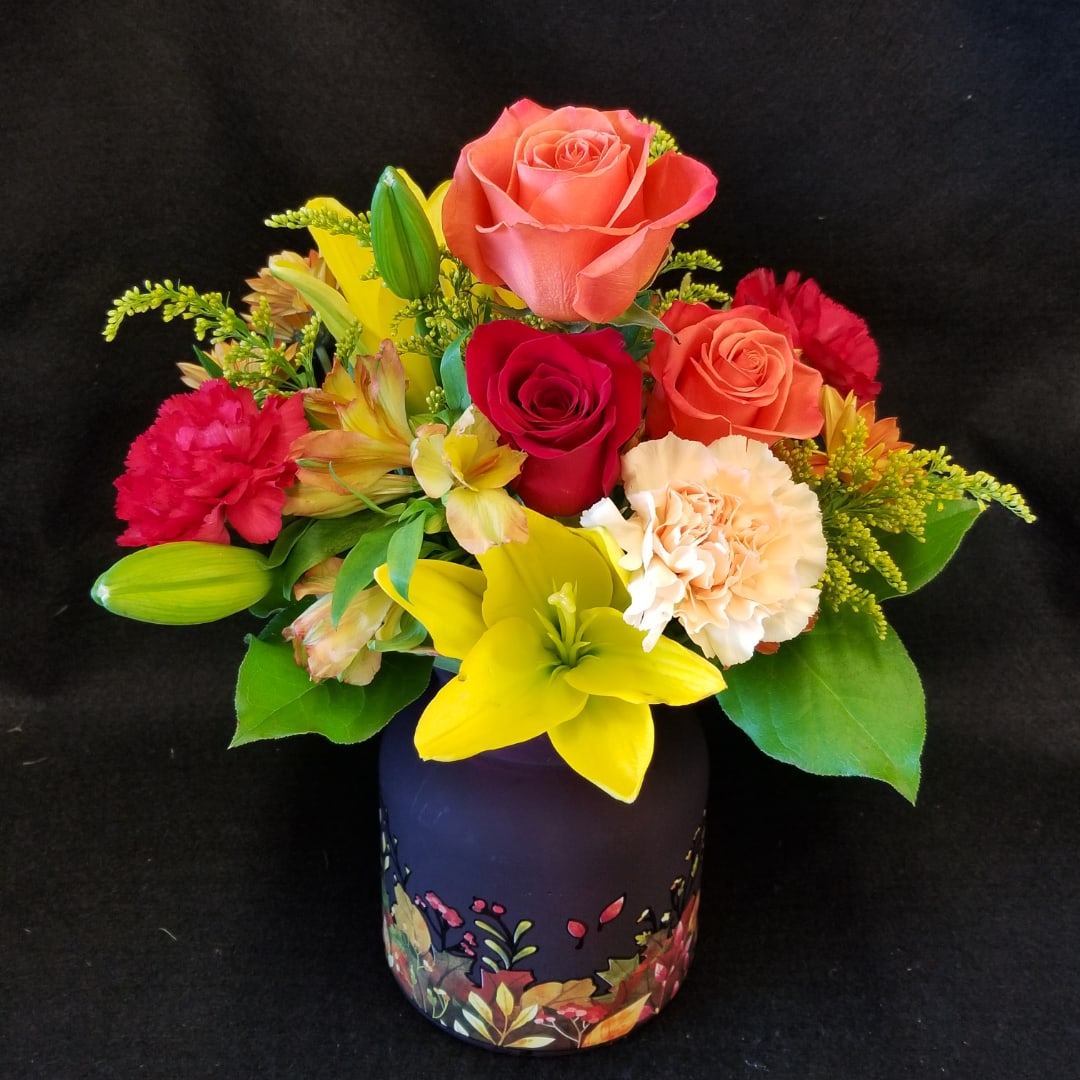 Mixed bouquet of roses, lilies, and carnations in a decorative vase