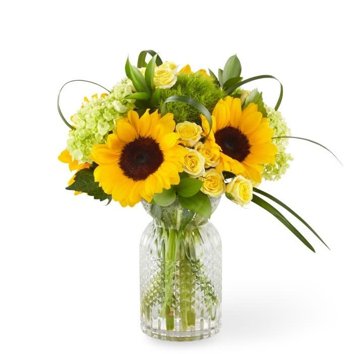 Sunflower and yellow rose arrangement in a clear glass vase