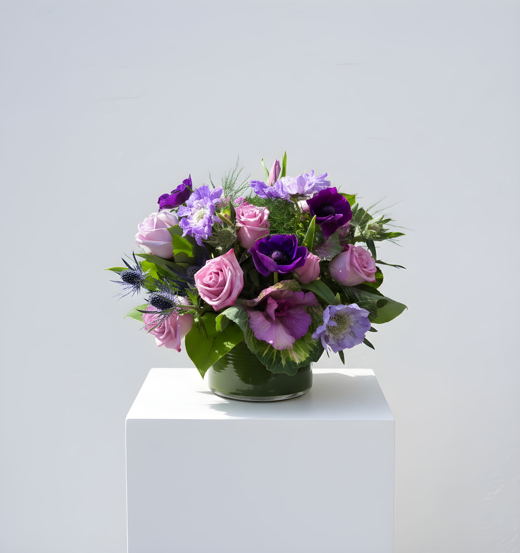 Sugar Plum Petals - A compact, romantic bouquet of purple blooms that reads like a soft daydream-perfect as a birthday bouquet or a just-because gift to make someone feel cherished. This flower arrangement combines roses and anemone with lavender and deep violet accents to create a rounded silhouette that feels both whimsical and thoughtfully composed; the result is the kind of gift that will make the person you're thinking of feel genuinely seen.