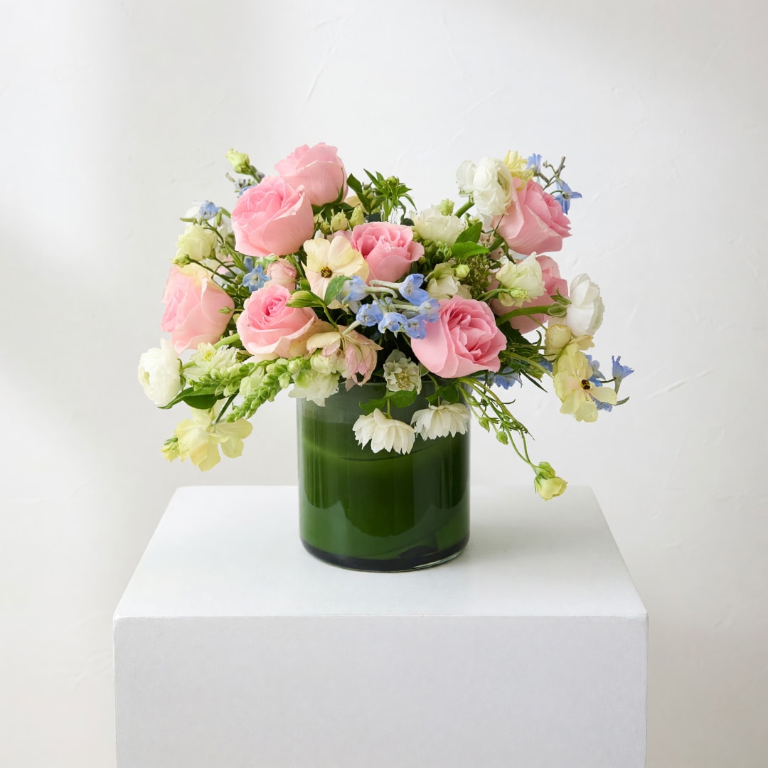 Pink and white roses in a green glass vase