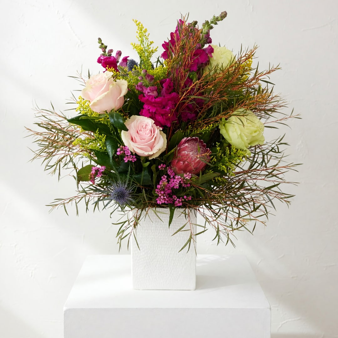 Mixed bouquet of pink and green flowers in a white vase