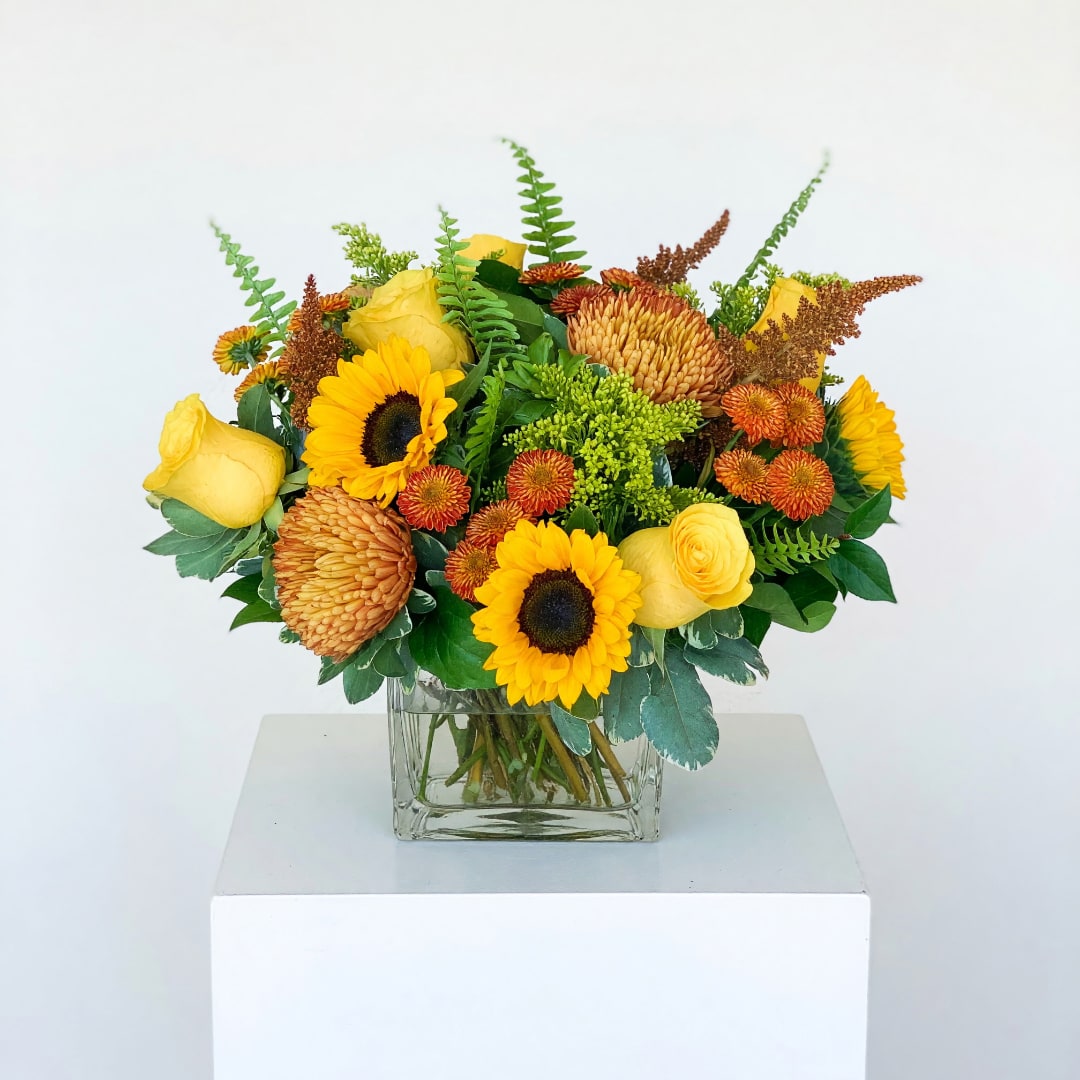 Yellow sunflower and rose arrangement in a clear square vase