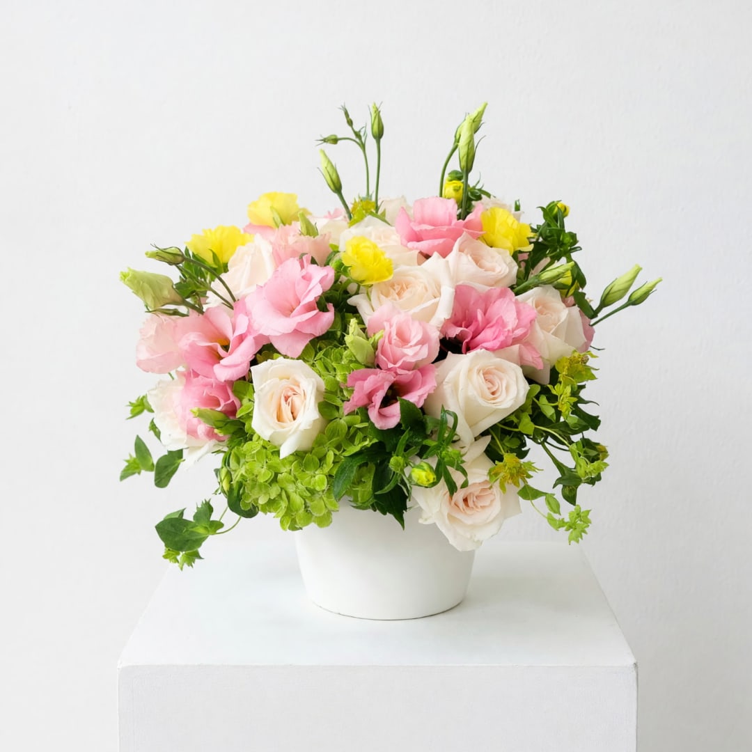 Pink and white roses with yellow blooms in a white vase