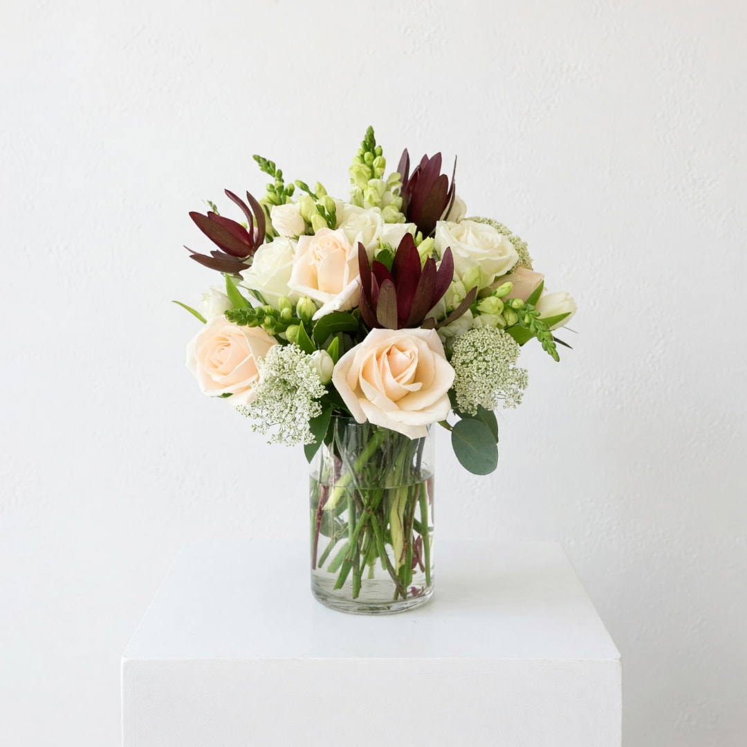 Bouquet of cream roses and white flowers in a clear glass vase
