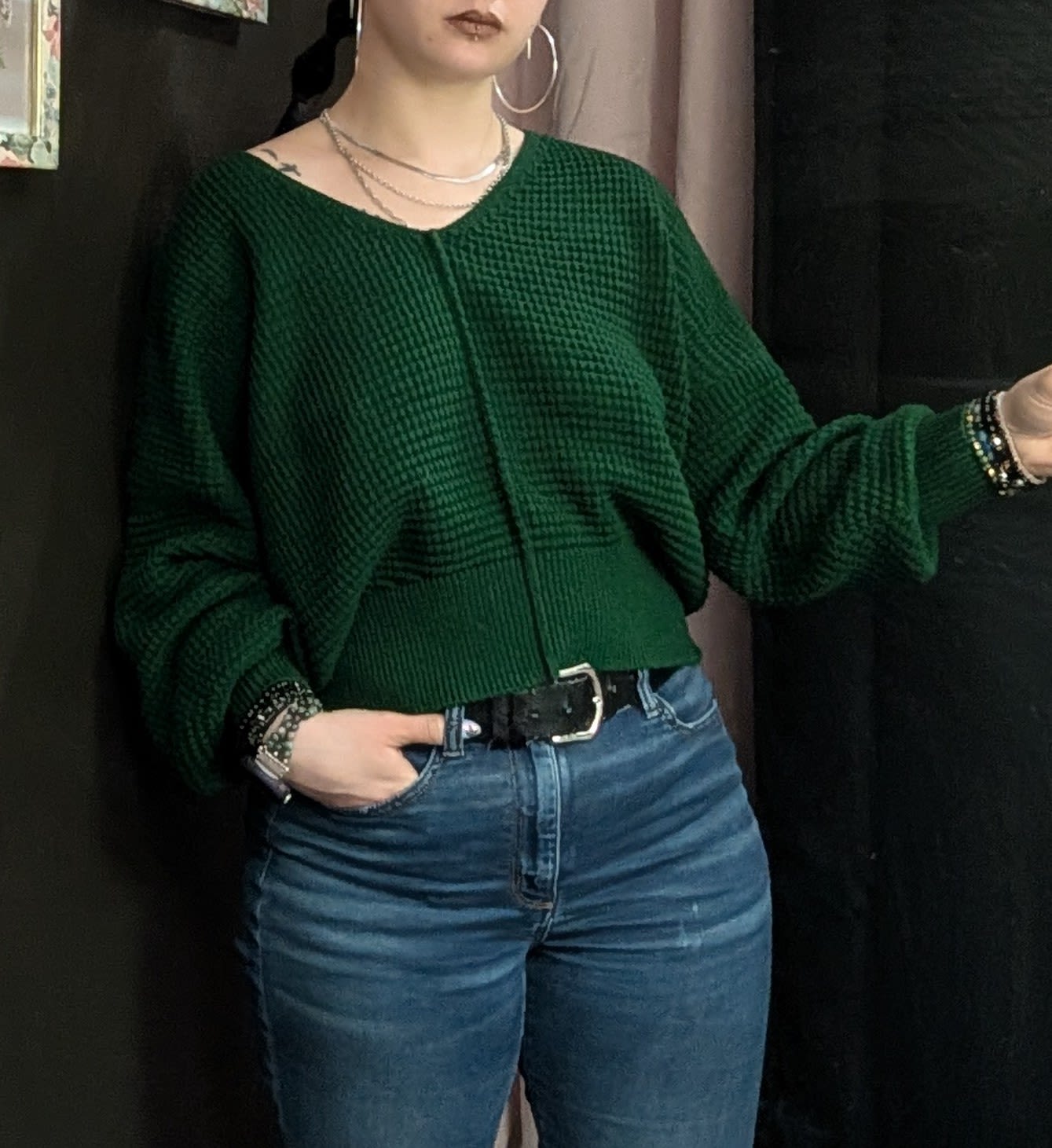 Person wearing a dark green sweater and blue jeans