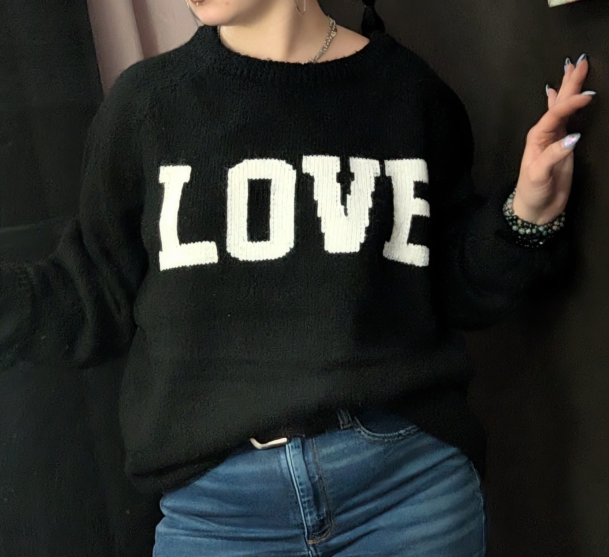 Person wearing a black sweater with the word LOVE in white letters