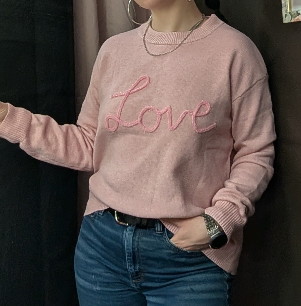 Person wearing a pink sweater with the word "Love" on it