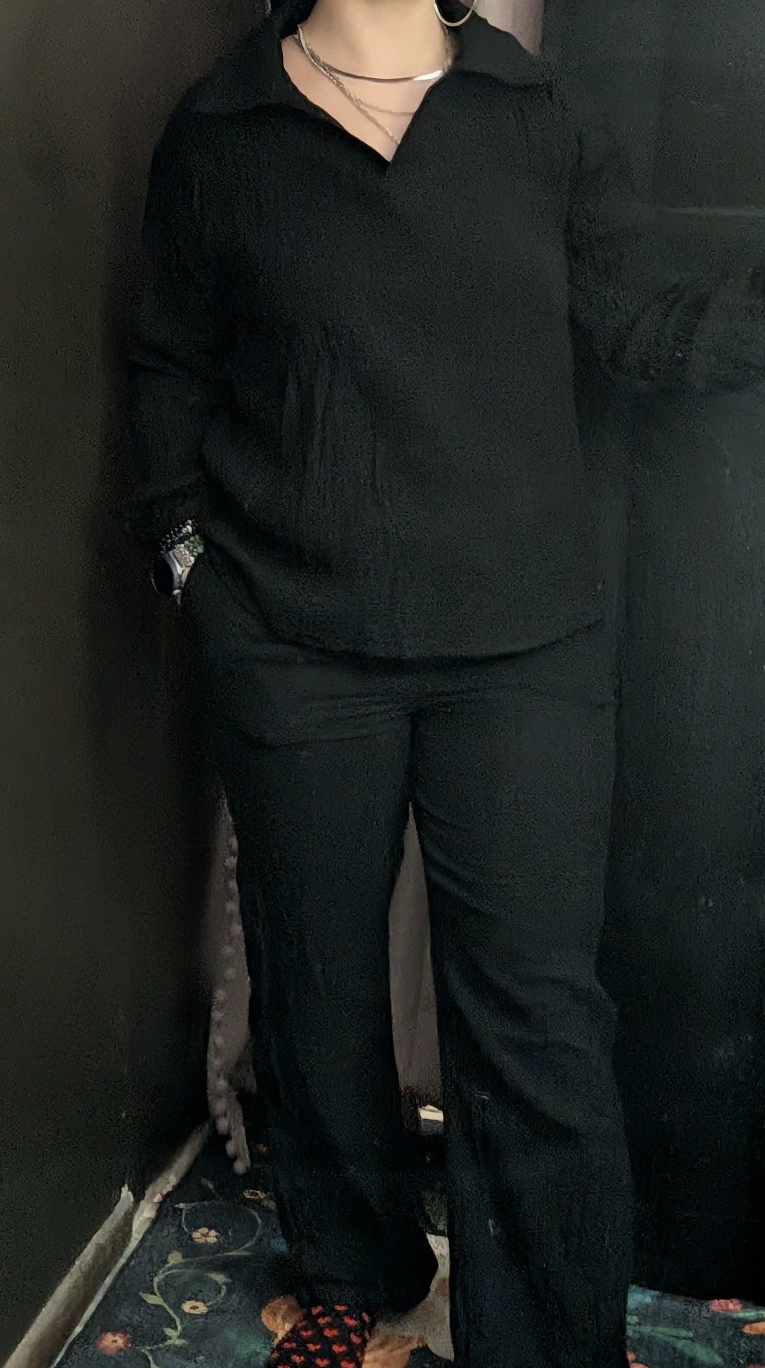 Person wearing black shirt and pants standing indoors