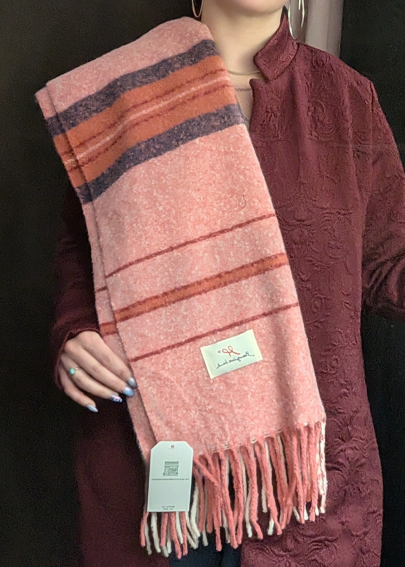 Person holding a pink striped scarf with fringe