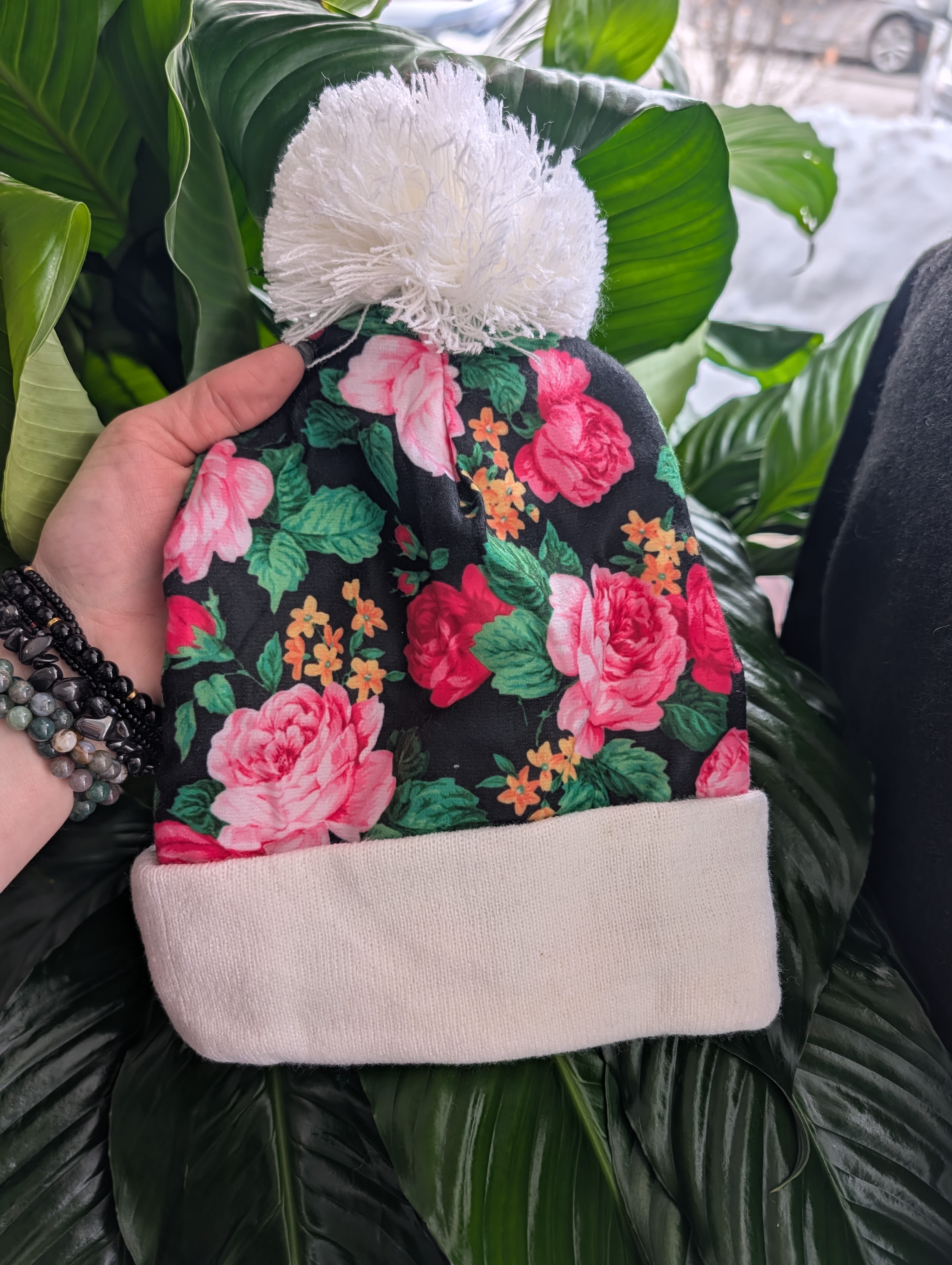 Floral knit beanie with pink roses and a white pom-pom