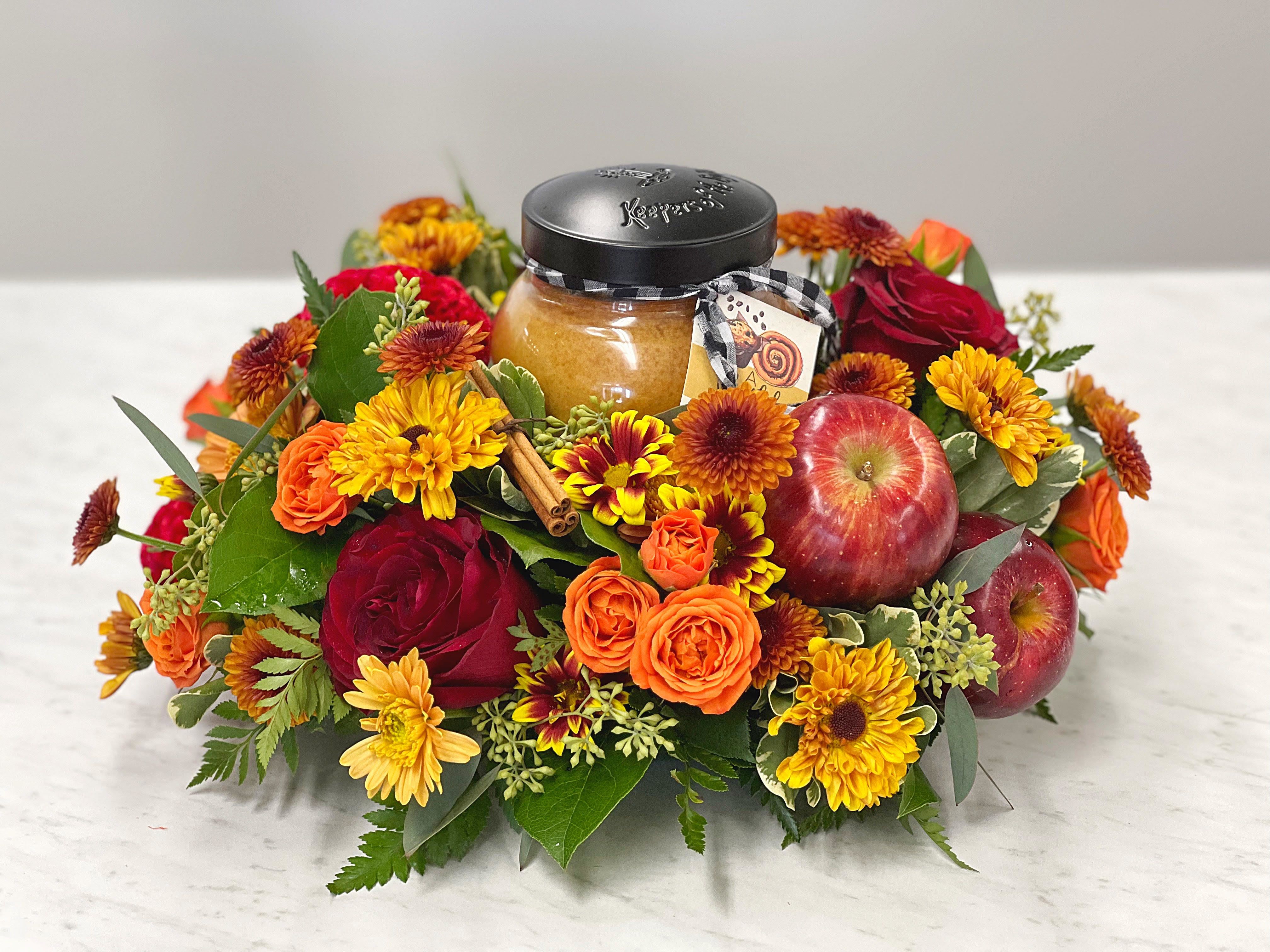 Autumn floral arrangement with apples and a jar candle in the center